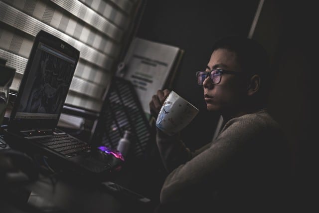 Women drinking from coffee mug while looking at a laptop