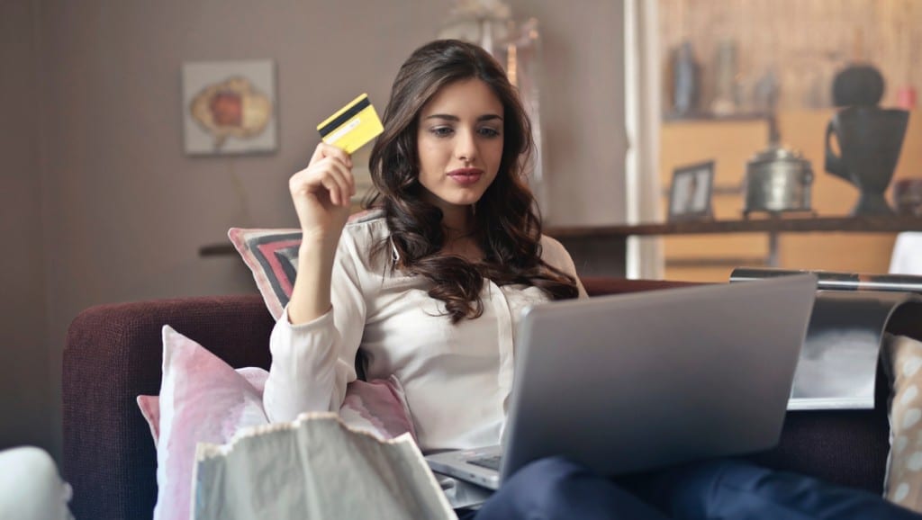 women holding a credit card while using a laptop