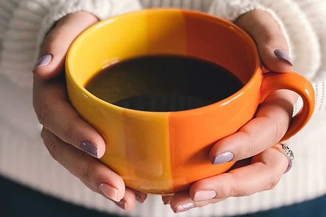 orange coffee mug in womans hands