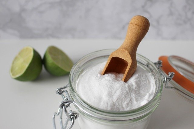 glass jar of baking soda with a scoop for spring cleaning