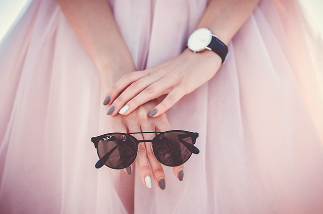 woman in pink dress holding ray bans sunglasses